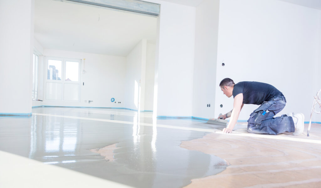 Plasterer during floor covering works with self-levelling cement mortar
