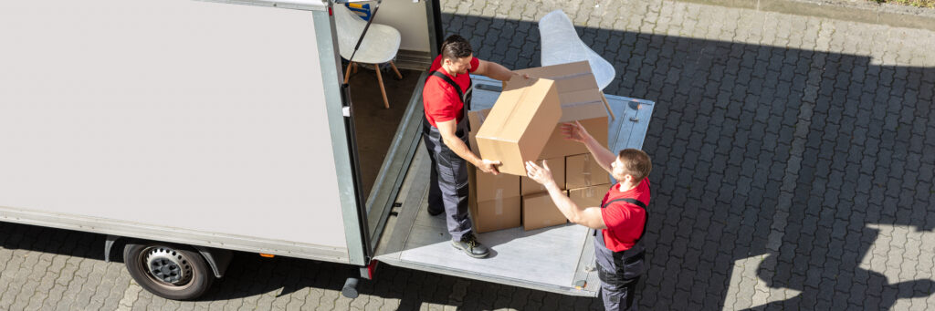 Male Movers Unloading The Cardboard Boxes Form Truck