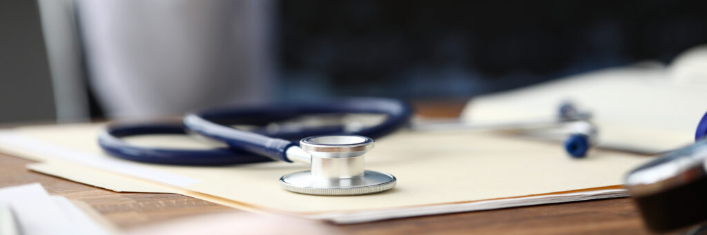 Medical stethoscope head lying at paper document on table