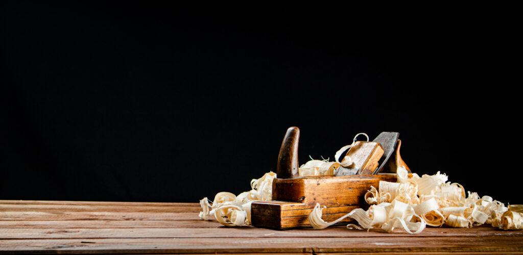 Hand planer on wood. On a black background.