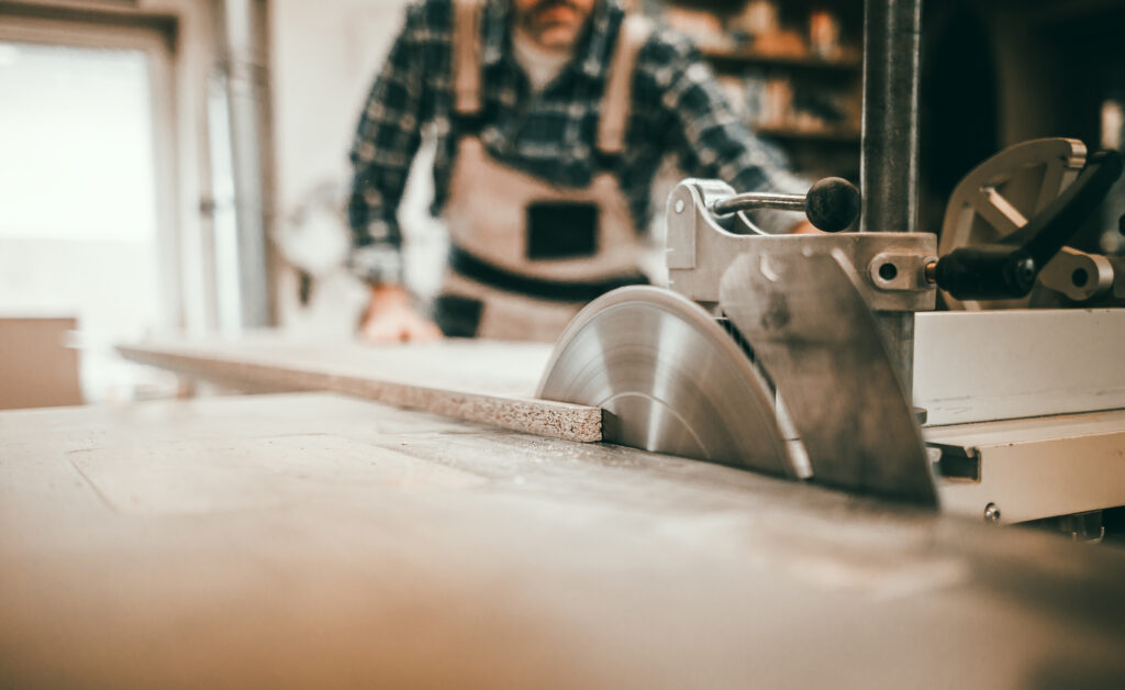 Close up of circular saw cutting wooden board in carpentry workshop